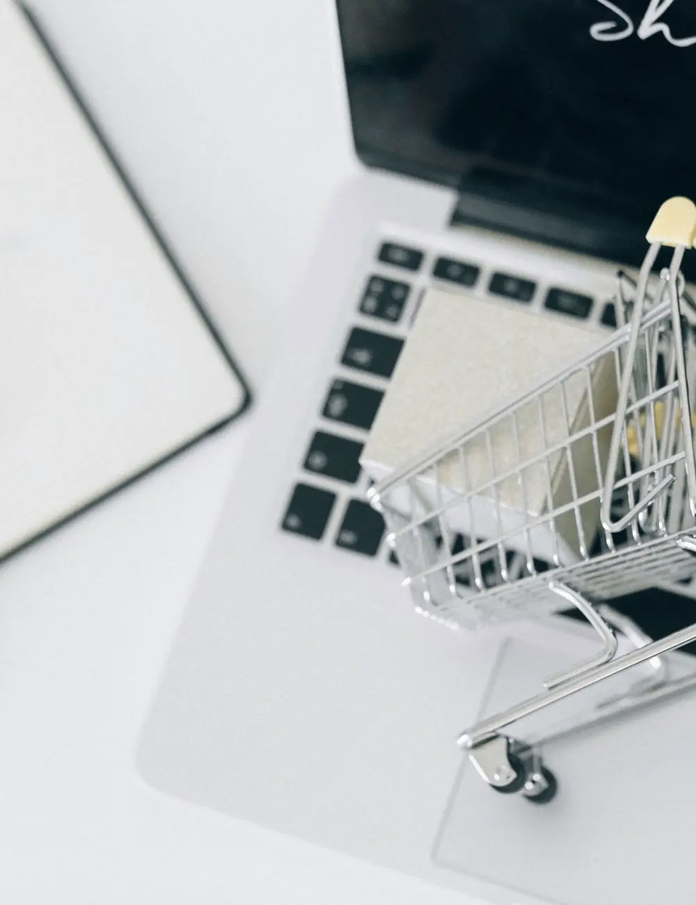 Carrinho de compras em miniatura sobre o teclado de um notebook